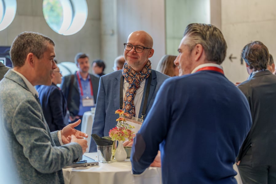 three business men, a mix of solutions providers and an executive, in conversation at a conference