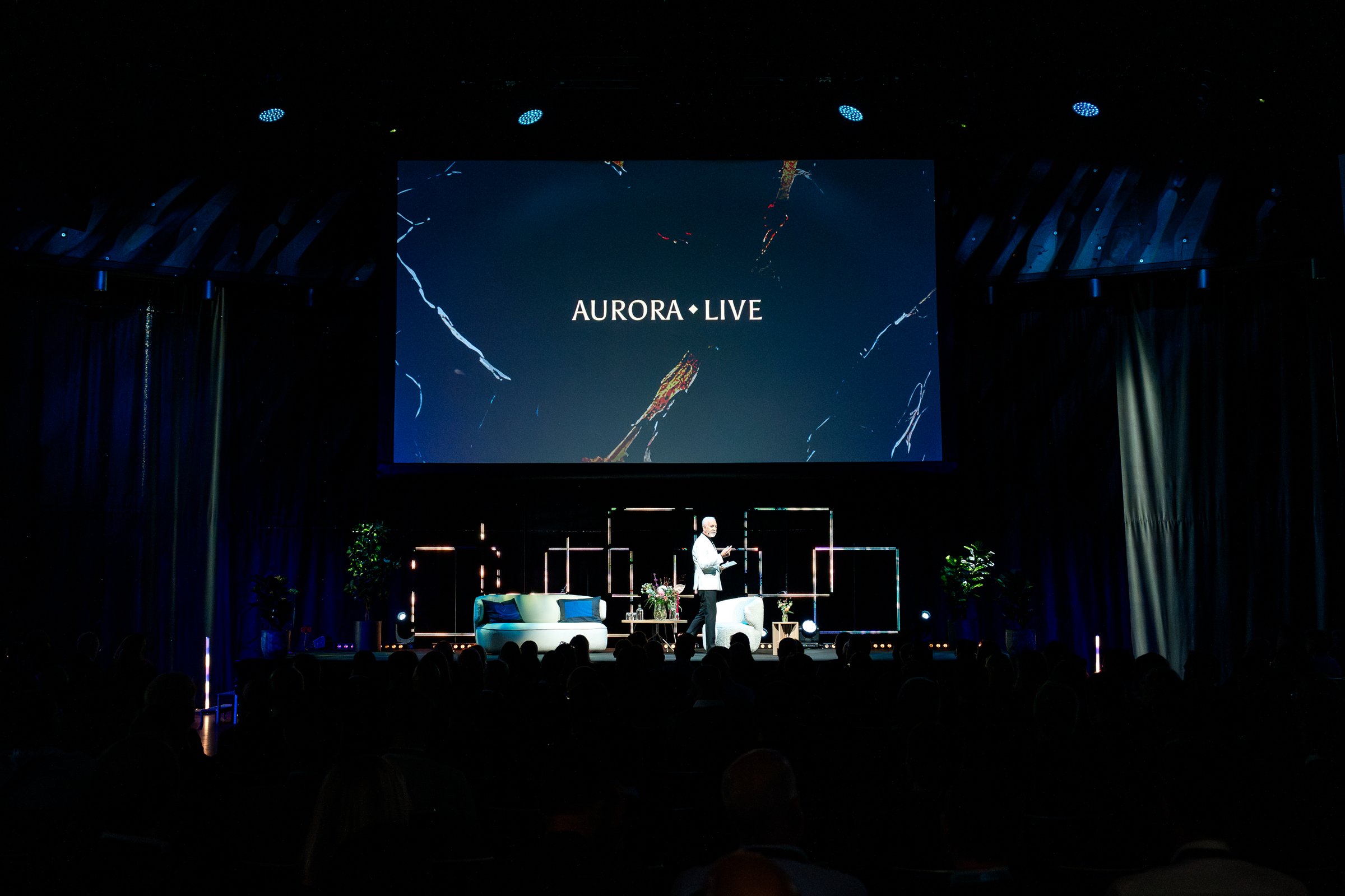 Man on stage giving keynote speech in front of 